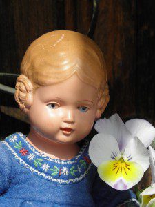 Das Foto zeigt ein Püppchen im Blumenstrauch.